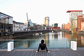 Mann sitzt auf einer Stufe im Düsseldorfer Medienhafen, moderne Architektur, Düsseldorf, Nordrhein-Westfalen, Landeshauptstadt von NRW, Deutschland