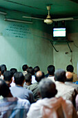 Egyptian people watching television in a communal room, Luxor, Egypt
