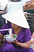 Woman eating noodles at a market, City Scape, Hoi An, Vietnam