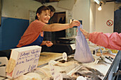 Woman selling fish at a fish market in St. Peter Port, Guernsey, Channel Islands, Great Britain