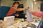 Frau verkäuft Fisch in einem Fischmarkt in St. Peter Port, Guernsey, Kanalinseln, Großbritannien