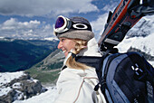 Eine Frau, Skifahrerin, trägt ihre Ski, Gebirge, Wintersport, Sport