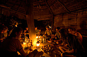 A group of people eating dinner in a typical hut, Madagascar, Africa