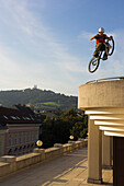 Junger Mann auf einem Trialbike springt über eine Mauer, Linz, Oberösterreich, Österreich