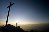 Hicker in front of summit cross of the Benediktenwand, Bavarian foothills of the Alps, Upper Bavaria, Bavaria, Germany