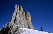 Backcountry skier beneath pinnacles of Vajolettuerme, Rosengarten Range, Dolomites, South Tyrol, Alta Badia, Italy