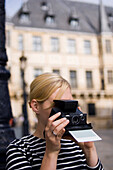 Woman taking picture with instant camera, Luxembourg