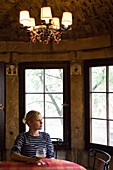 Frau schaut aus dem Fenster mit einem Weinglas in der Hand, Luxemburg