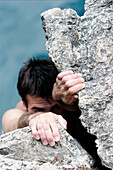 Junger Mann klettert an einem Felsen, Alpsee, Schwangau, Bayern, Deutschland