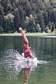 Young man jumping into a lake, Fuessen, Bavaria, Germany