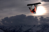 Snowboarder juming at sunset, See, Tyrol, Austria