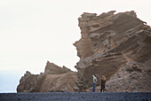 A couple looking at rock formations on the beach at El Golfo, Lanzarote, Canaries, Canary Islands, Spain, Europe