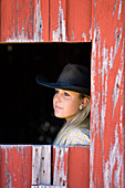 Cowgirl schaut aus Scheunenfenster, Wilder Westen, Oregon, USA