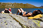 Young couple sunbathing on rock at lake Laghi della Valletta, Gotthard, Canton of Ticino, Switzerland