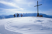Group of hikers at summit cross, mount Wandberg with view to Wilder and Zahmer Kaiser range, Chiemgau Alps, Upper Bavaria, Bavaria, Germany