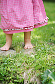 Bar-footed girl wearing a pink dress on grass, , Carinthia, Austria