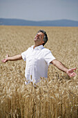 Man with outstreched arms standing in a corn field, Carinthia, Austria