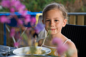 Junges Mädchen genießt Spaghetti auf Terrasse von Ferienhaus, Henne Strand, Jütland, Dänemark, Europa