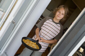 Boy holding a pan with scrambled eggs, Sylt island, Schleswig-Holstein, Germany