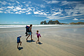 Family hiking on Wharariki Beach, low tide, near Puponga, northwestern coast of South Island, New Zealand