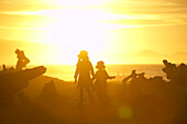Kinder laufen zwischen Treibholz,  Sonnenuntergang, Strand bei Haast, Westküste, Südinsel, Neuseland