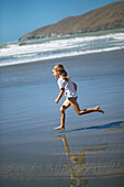 Girl running at the beach of Little Okains Bay at low tide, Okains Bay, Bank`s Peninsula, east coast, South Island, New Zealand