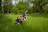 Family hand in hand running over meadow, MR