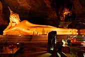 Liegender Buddha und buddhistischer Mönch in der Tham Yai  Höhle beim Kloster Wat Suwan Kuha, Phang Nga, Thailand