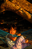 Thai girl sitting in a hammock on the beach, Surin Islands Marine National Park, Headquarters, Ko Surin, Phang Nga, Thailand