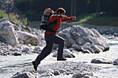 Mann springt über Bach, Obere Loisach, Garmisch-Partenkirchen, Bayern, Deutschland