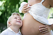 Boy (4-5 years) putting ear to pregnant mother's belly, Styria, Austria