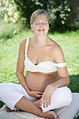 Pregnant woman with closed eyes sitting on grass, Styria, Austria