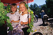 Two children, girls, sitting in a carriage decorated with grape leaf, Festival, Glen Ellen, Sonoma Valley, California, USA
