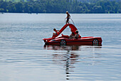 Familie mit Kindern auf Tretboot in Form eines Sportwagens mit Rutsche, Riegsee, Oberbayern, Bayern, Deutschland