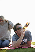 Mann liegt auf Decke und trinkt eine Flasche Bier, Ambach, Starnberger See, Bayern, Deutschland