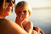 Mother and son at lakeshore of Lake Starnberg, boy picking his nose, Ammerland, Bavaria, Germany