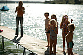Children blowing bubbles on jetty, Woerthsee, Upper Bavaria, Bavaria, Germany