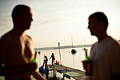 Kinder spielen am Holzsteg, Zwei Männer trinken Bier, Wörthsee, Oberbayern, Deutschland