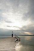 Man standing on jetty at Lake Starnberg, Muensing-St. Heinrich, Upper Bavaria, Bavaria, Germany, MR