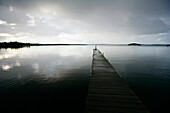 Eine Person steht auf einem Steg, Holzsteg am See, Wolkenhimmel, Madkroken in der Nähe von Växjö, Smaland, Schweden