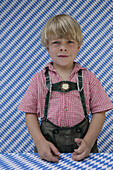 Sad boy (4-5 years) wearing leather trousers looking at camera, Munsing, Upper Bavaria, Bavaria, Germany