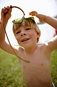 Boy (4-5 years) using a water lily leave as hat, Lake Staffelsee, Upper Bavaria, Bavaria, Germany