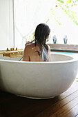 Mid adult woman using shower in bathtub, Styria, Austria
