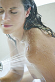 Mid adult woman using shower in bath, Styria, Austria