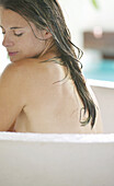 Frau sitzt mit geschlossenen Augen in der Badewanne, Steiermark, Österreich