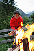 Woman making a campfire, Heiligenblut, Hohe Tauern National Park, Carinthia, Austria