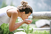 Woman refreshing at a font, Heiligenblut, Hohe Tauern National Park, Carinthia, Austria