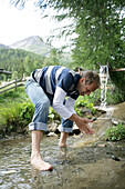 Man cooling himself in a creek near Heiligenblut, Hohe Tauern National Park, Carinthia, Austria