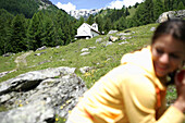 Kleine Kirche auf einer Alm, Frau sitzt im Vordergrund, Heiligenblut, Nationalpark Hohe Tauern, Kärnten, Österreich