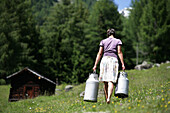 Frau mit Milchkannen auf einer Alm, Heiligenblut, Nationalpark Hohe Tauern, Kärnten, Österreich